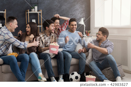 Excited friends watching football match at home 42983827
