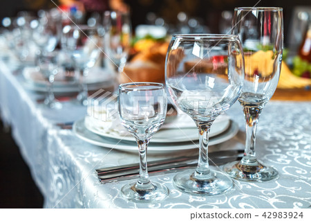 Table setting with glasses, plates, napkins and food 42983924