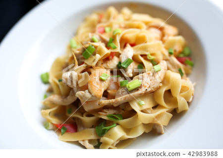 Pasta with chicken and vegetables on white plate. Wooden table background. Close up food photo Pasta with chicken and vegetables on white plate. Wooden table background. Close up food photo 42983988