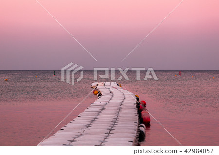 Road in the sea. Wooden Pier, leaving the horizon of the ocean. Water on the sunset. Landscape in 42984052