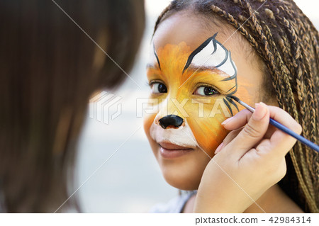 Little girl getting her face painted by face painting artist. Little girl getting her face painted by face painting artist. 42984314