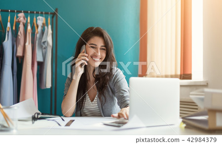 Young pretty fashion designer in studio working at order 42984379