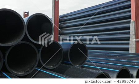 Warehouse of finished plastic pipes industrial outdoors storage site. Manufacture of plastic water Warehouse of finished plastic pipes industrial outdoors storage site. Manufacture of plastic water 42986749
