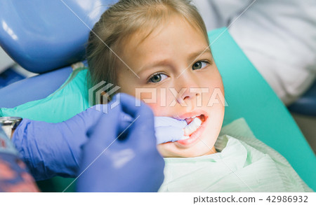 Child with a mother at a dentist's reception. The girl lies in the chair, behind her mother. The Child with a mother at a dentist's reception. The girl lies in the chair, behind her mother. The 42986932