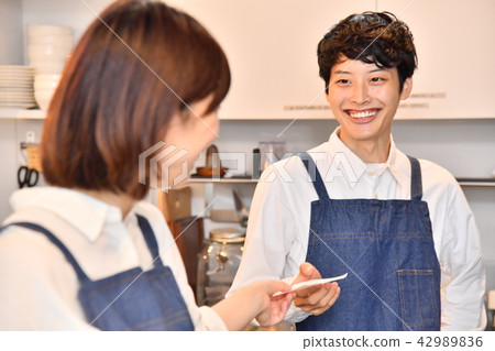 A female clerk who hands an order slip to a cafe male clerk A female clerk who hands an order slip to a cafe male clerk 42989836