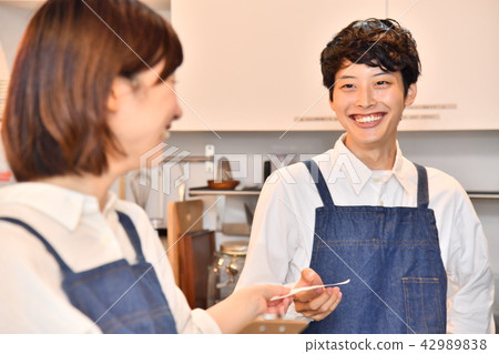 A female clerk who hands an order slip to a cafe male clerk A female clerk who hands an order slip to a cafe male clerk 42989838