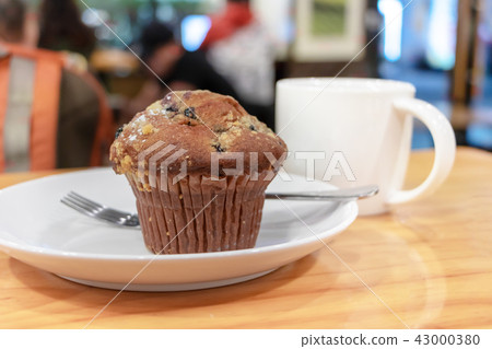 Blueberry homemade muffin with chocolate chip and cup of coffee with milk Blueberry homemade muffin with chocolate chip and cup of coffee with milk 43000380