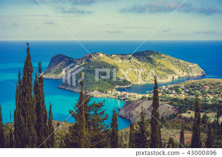 View to Assos village in sun light and beautiful blue sea. Cypress trees in foreground. Kefalonia 43000896