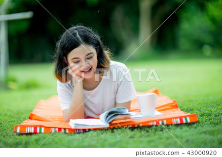 asian girl lying prone on a mat and reading a book 43000920