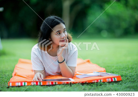 Asain girl lying prone on a mat with a tablet 43000923