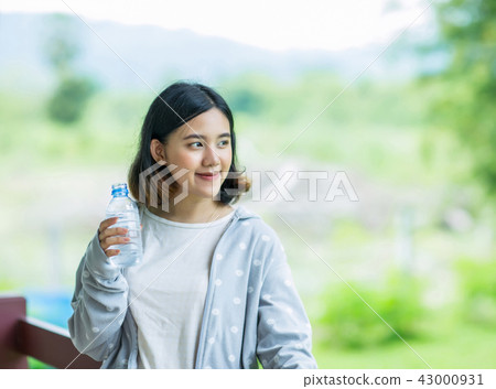 Pretty asian woman holding a bottle ofcold water 43000931