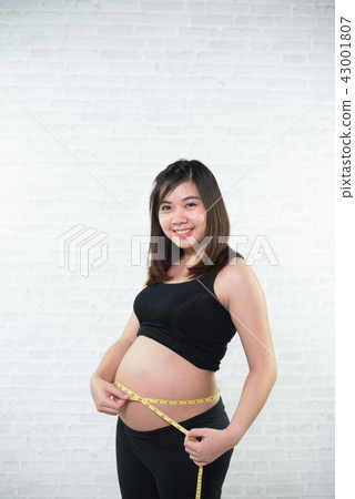Pregnant woman measures belly circumference 43001807