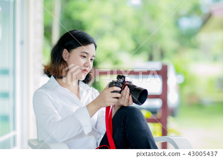 Young asian woman sitting and holding camera 43005437