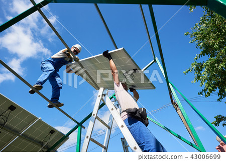 Workers command installing solar panels on the roof. 43006699