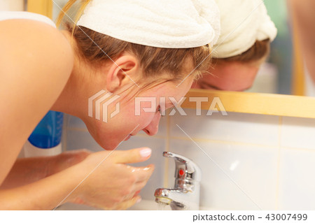 Woman washing face in bathroom. Hygiene Woman washing face in bathroom. Hygiene 43007499