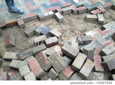 Construction workers installing concrete pavers 43007956