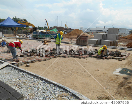 Construction workers installing concrete pavers 43007966