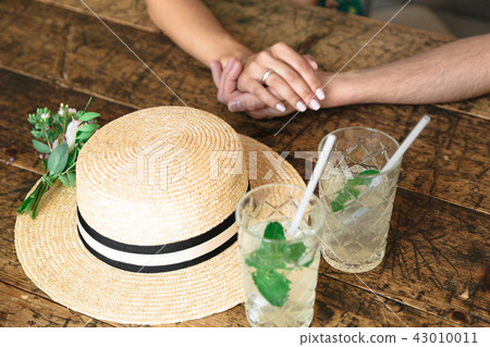 Hands of lovers near a straw hat Hands of lovers near a straw hat 43010011