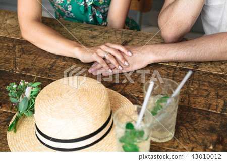 Hands of lovers near a straw hat 43010012