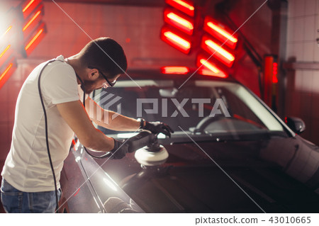 Car detailing - man with orbital polisher in auto repair shop. Selective focus. 43010665