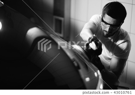 Car detailing - man with orbital polisher in auto repair shop. Selective focus. 43010761