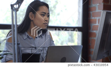 Pretty ethnic girl working at computer desk Pretty ethnic girl working at computer desk 43010954
