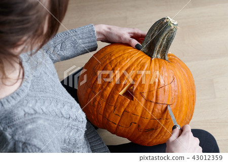 Carving halloween pumpkin into jack-o-lantern, close up view Carving halloween pumpkin into jack-o-lantern, close up view 43012359