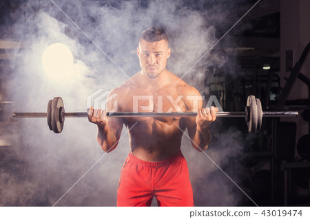 Handsome power athletic man with barbell. Strong bodybuilder with six pack, perfect abs, shoulders 43019474