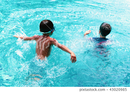 Little boy playing in swimming pool with friend Little boy playing in swimming pool with friend 43020985
