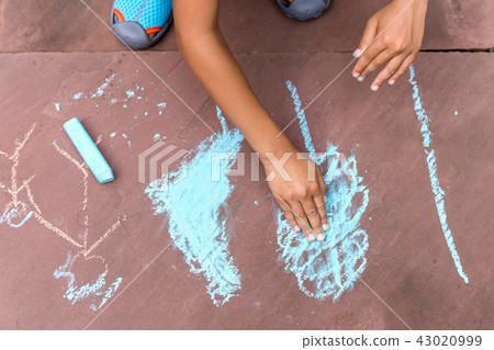 Boy drawing with coloured chalk on brick floor Boy drawing with coloured chalk on brick floor 43020999
