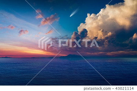 Bright comet in glowing sunset sky above dark sea 43021114