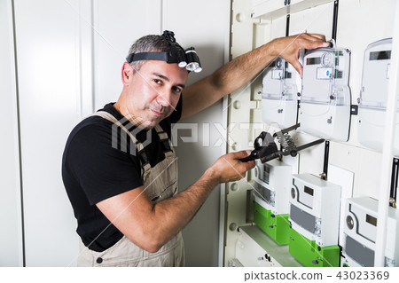 Electrician testing equipment in fuse switch box 43023369