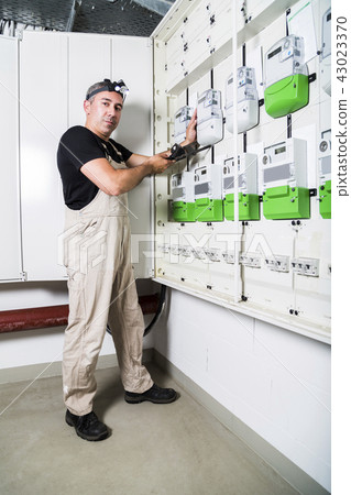 Electrician testing equipment in switch box 43023370