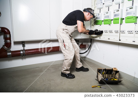 Electrician testing switch box by measuring device 43023373