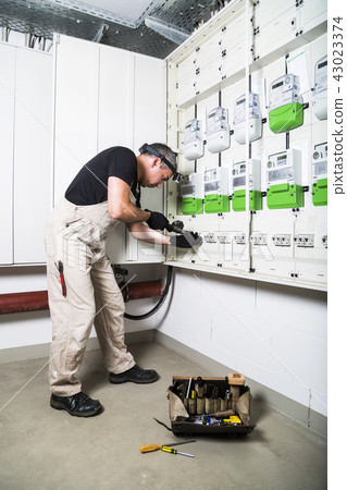 Electrician testing fuse box by measuring device Electrician testing fuse box by measuring device 43023374