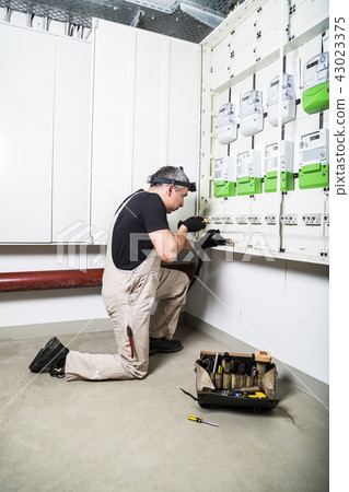 Electrician fixing fuse box or switch box 43023375