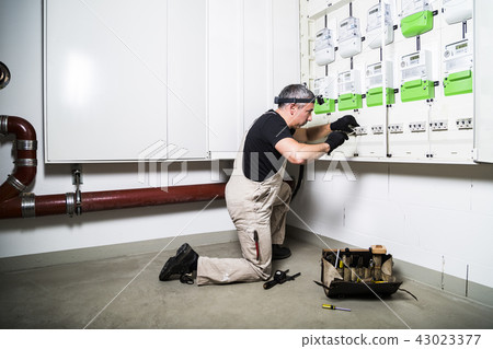 Electrician with box of tools fixing switch box Electrician with box of tools fixing switch box 43023377