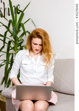 Business and training. beautiful young red haired long hair Caucasian woman uses laptop while 43029086
