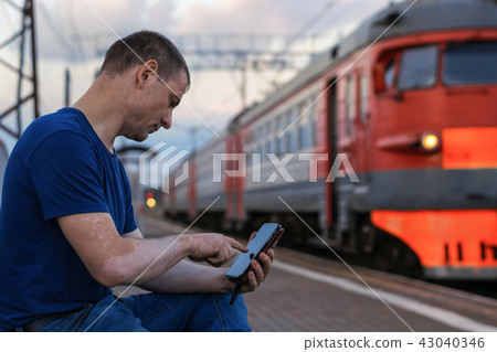 A man with a smartphone at the train station A man with a smartphone at the train station 43040346