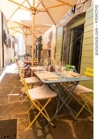 Small caffee, restaurant in narrow street in a medieval town with colorful tables and chairs Small caffee, restaurant in narrow street in a medieval town with colorful tables and chairs 43042542