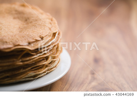 Stack of fresh hot crepes or blinis on wood table with copy space 43044169