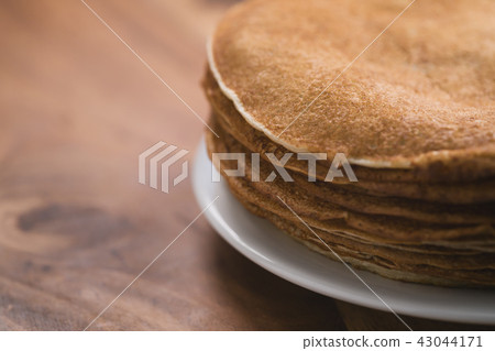 Stack of fresh hot crepes or blinis on wood table with copy space 43044171
