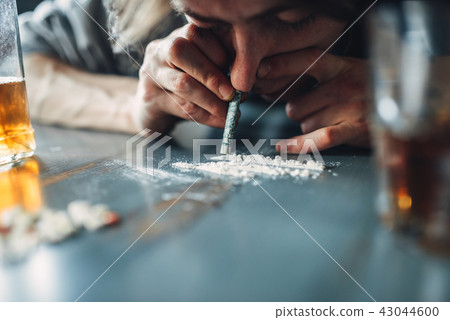 Male junkie sniffing a line of cocaine 43044600