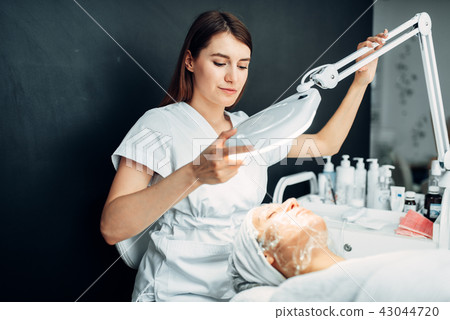 Beautician watches on patient face in mask Beautician watches on patient face in mask 43044720