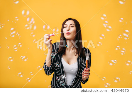 Woman with soap bubbles, yellow background 43044970