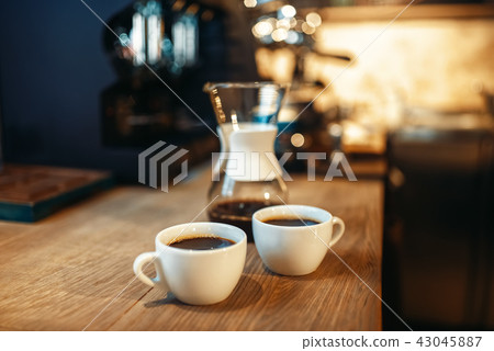 Two cups of fresh black coffee on wooden counter Two cups of fresh black coffee on wooden counter 43045887