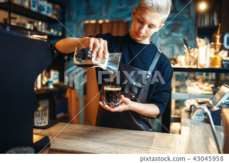 Male barista in apron makes fresh black coffee Male barista in apron makes fresh black coffee 43045958