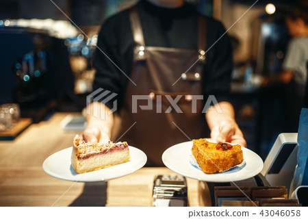 Barista holding in hands plates with sweet dessert 43046058