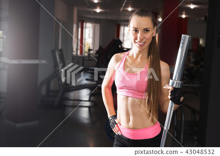 beautiful woman standing with a barbell at the gym 43048532