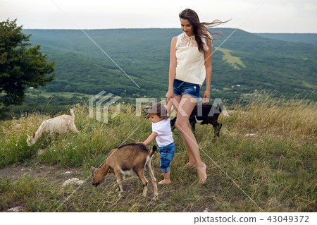 woman with a child in a field on the mountain woman with a child in a field on the mountain 43049372